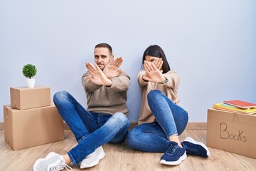 Canvas Print - Young couple moving to a new home rejection expression crossing arms and palms doing negative sign, angry face