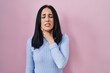© Krakenimages.com - Hispanic woman standing over pink background touching painful neck, sore throat for flu, clod and infection