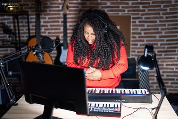 Sticker - Plus size hispanic woman playing piano at music studio with hand on stomach because nausea, painful disease feeling unwell. ache concept.