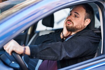 Wall Mural - Young hispanic man driving car with desperate expression at street