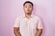 © Krakenimages.com - Chinese young man standing over pink background relaxed with serious expression on face. simple and natural looking at the camera.
