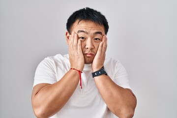 Poster - Young chinese man standing over white background tired hands covering face, depression and sadness, upset and irritated for problem