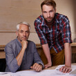 © Miko/peopleimages.com - Architecture, teamwork and portrait of men in workshop with blueprint for building construction. Senior engineer, serious father and son working on design, project and plan of apprentice and mentor.