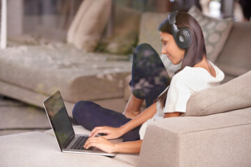 Canvas Print - Headphones, typing and woman with laptop on home sofa listening to music, audio or streaming movies. Happy female student relax on couch to listen to podcast or research to learn language on internet