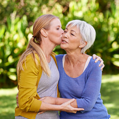 Wall Mural - Adult daughter kiss mother, hug and trust with peace outdoor, family spending quality time in garden together. Women embrace while they relax in park, love and care with bonding and affection