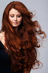 Wall Mural - Wind in hair, ginger and face of woman in studio for keratin treatment, wellness and growth on gray background. Beauty, hairdresser mockup and female model with shine, healthy and natural hairstyle