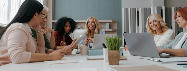 Sticker - Group of confident mature women discussing business while having meeting in the office