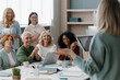 © gstockstudio - Group of mature women listening to speaker while having business training in office