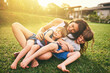 Mother, children and hug playing on grass for fun bonding in the sun outside their house in nature. Happy mom hugging kids on garden floor outdoors in playful, joy and happiness of family together
