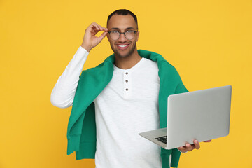 Sticker - Happy young intern holding laptop on orange background