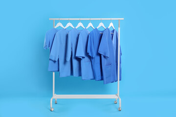 Poster - Medical uniforms on rack against light blue background