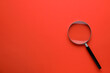 Magnifying glass on red background, top view. Space for text