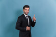 Confident businessman in formal suit pointing finger up to indicate promotion or advertising with excited and amazed facial expression and gesture on isolated background. Fervent