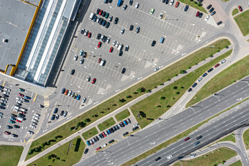 Wall Mural - shopping mall parking lot with many parked cars. top view aerial photo in sunny summer day.