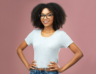 Poster - Portrait, happy and black woman with glasses akimbo in studio isolated on a pink background. Natural beauty, nerd and face of African female model from Nigeria with confidence, cosmetics and fashion.