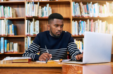 University. library and student on laptop with research, planning or learning for exam, report or focus on studying, goals and education. Black man, college and working on task, essay or scholarship