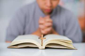 Close-up of a woman reading an open bible, praying and holding hands on her bible. Spiritual or bible study concept.