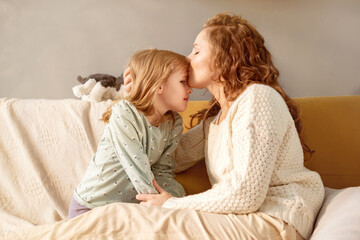 mom cuddling little girl , mother kissing little daughter on head, sharing close tender moment toget