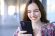 © Antonioguillem - Happy woman using smartphone in a street