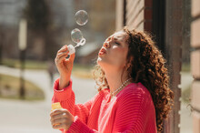 Young Woman Blowing Soap Bubbles Through Wand