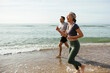 © Westend61 - Happy mature couple laughing and running in water at beach