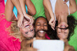 © Westend61 - Happy friends imitating mustache lying on colorful blanket