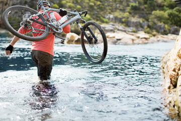 Wall Mural - Man carrying mountain bike in river