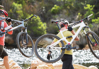 Wall Mural - Men carrying mountain bikes in river