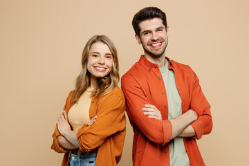 Side view young smiling happy fun cool couple two friends family man woman wear casual clothes hold hands crossed folded together isolated on pastel plain light beige color background studio portrait.