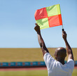 Flag, foul and man soccer referee in football match or game wave to stop play during sport training or workout. Hand, sports and person or assistant official raise or signal mistake in sky background