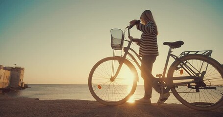 Wall Mural - Carefree woman with bike riding on beach having fun, on the seaside promenade on a summer day. Summer Vacation. Travel and lifestyle Concept.