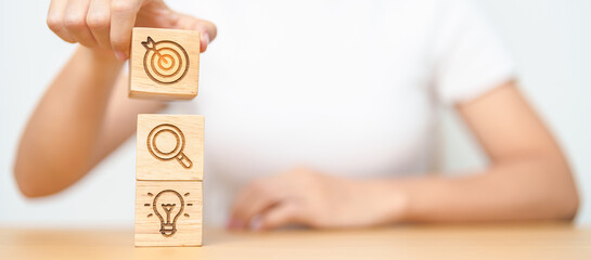 Woman hand holding dartboard above magnifying and Lightbulb icon block. business planning process, goal, vision, strategy, target, mission, action, research, teamwork and idea concept