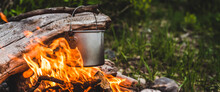 Kettle Hanging Over Fire. Cooking Food At Fire In Wild. Beautiful Big Log Burns In Bonfire Close-up. Survival In Wild Nature. Wonderful Flame With Caldron. Pot Hangs In Flames. Campfire Background.