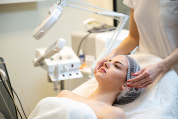 Wall Mural - Beautiful young woman relaxing with face massage at beauty spa