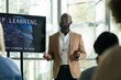© pressmaster - Young black man in formalwear standing by interactive board while explaining points of his presentation to audience during conference