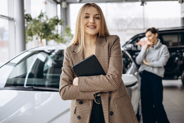 Wall Mural - Woman choosing a car with dealership in a car showroom