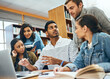 © K Seisa/peopleimages.com - Education, talking and students studying in a library for a group project, teamwork and learning. Diversity, laptop and friends speaking about university notes, knowledge and planning research