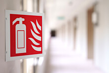 Close-up Image Features An Emergency Sign Of A Fire Extinguisher In A Building Corridor. The Image Has A Selective Focus, Drawing Attention To The Fire Extinguisher Sign.