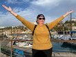 Senior woman with backpack staying in marina on old city of Antalya Turkey near ships, yachts and boats. Summer active tourism for pensioner. adventure is ageless,