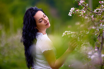 Wall Mural - portrait of a beautiful brunette woman in a blossoming apple orchard