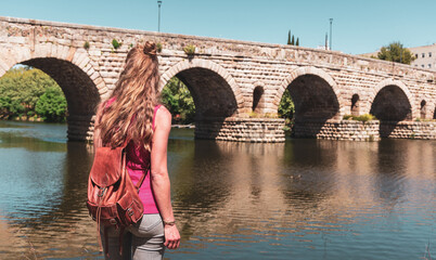 Wall Mural - Woman tourist enjoying old roman bridge in Spain- Merida, Extramadura