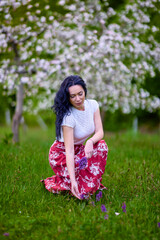 Wall Mural - portrait of a beautiful brunette woman in a blossoming apple orchard