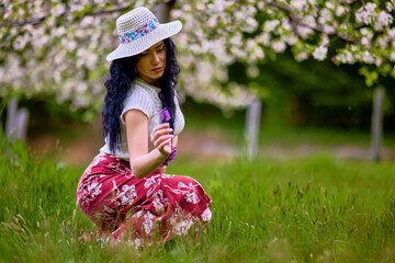 Wall Mural - portrait of a beautiful brunette woman in a blossoming apple orchard