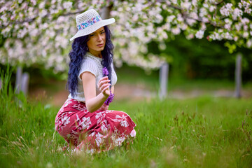 Wall Mural - portrait of a beautiful brunette woman in a blossoming apple orchard