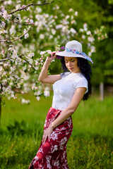 Wall Mural - portrait of a beautiful brunette woman in a blossoming apple orchard