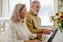 Senior Couple Playing On Piano Together At Home.