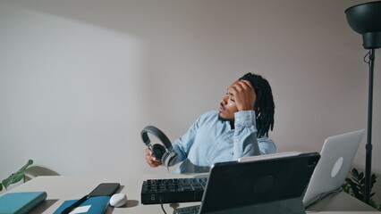 Freelance guy taking headphones off apartment closeup. Tired arranger relaxing