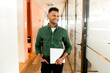 © Vadim Pastuh - Waist up portrait of the proud indian businessman carrying laptop in hand and smiling, Latin freelancer man posing in modern loft office with glass partition on the background, looks aside