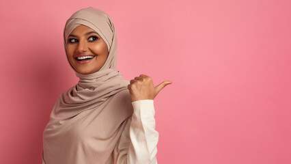 Happy Muslim Woman In Hijab Pointing At Copy Space Behind Her Back