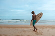 © shintartanya - company of young guys Sri Lankans, Indians surfers on the ocean coast with a surfboard, sporty tanned body, smiling and running with a surfboard on the beach on a sunny summer day, ready to surf.